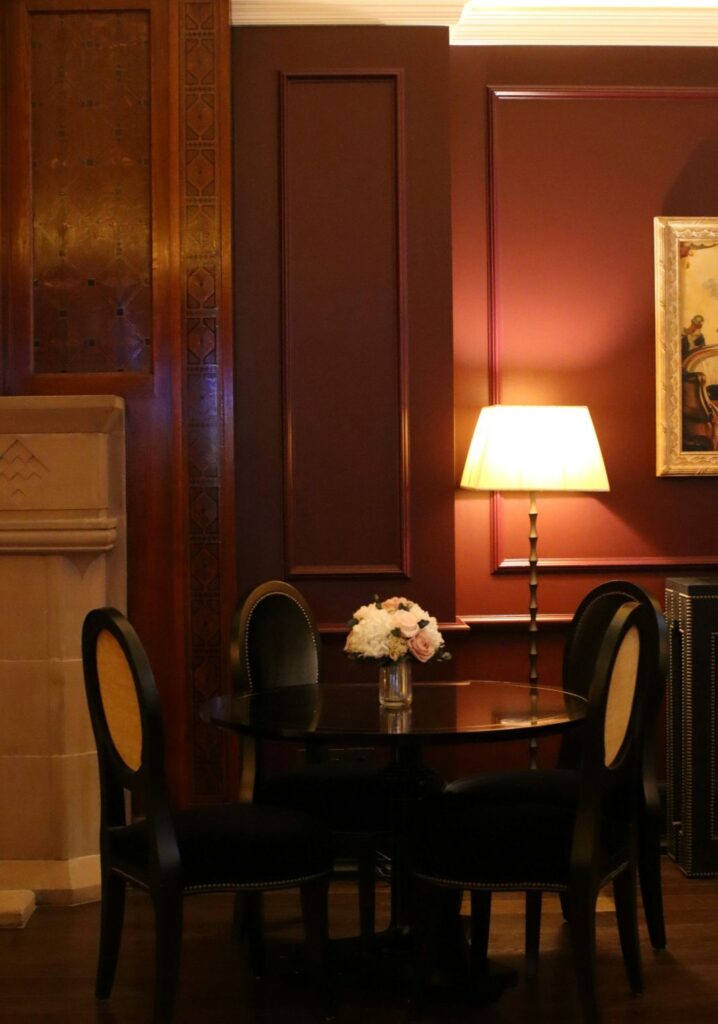 In this refined setting, a classic black dining table sits elegantly under warm lighting, surrounded by timeless decor and upholstered chairs. It’s well suited for formal dining areas or upscale restaurants that favour a m