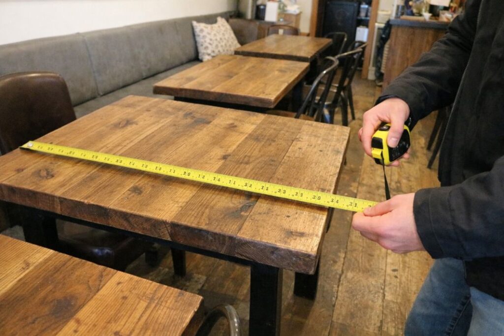 an illustrative image of a wooden table being measure in a cafe